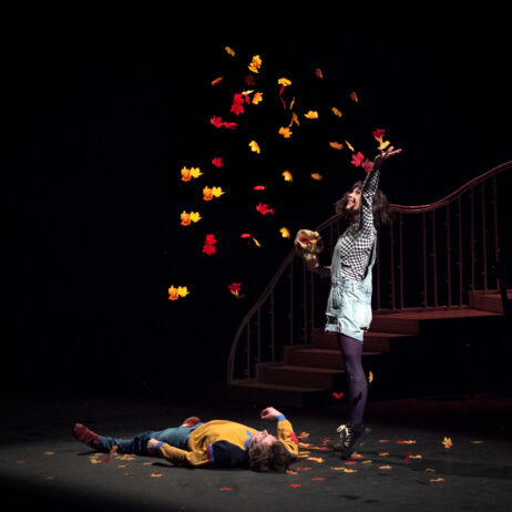 Photo du spectacle Courgette : une femme jette des feuilles rouges jaunes et oranges en l'air, au dessus d'un homme allongé par terre